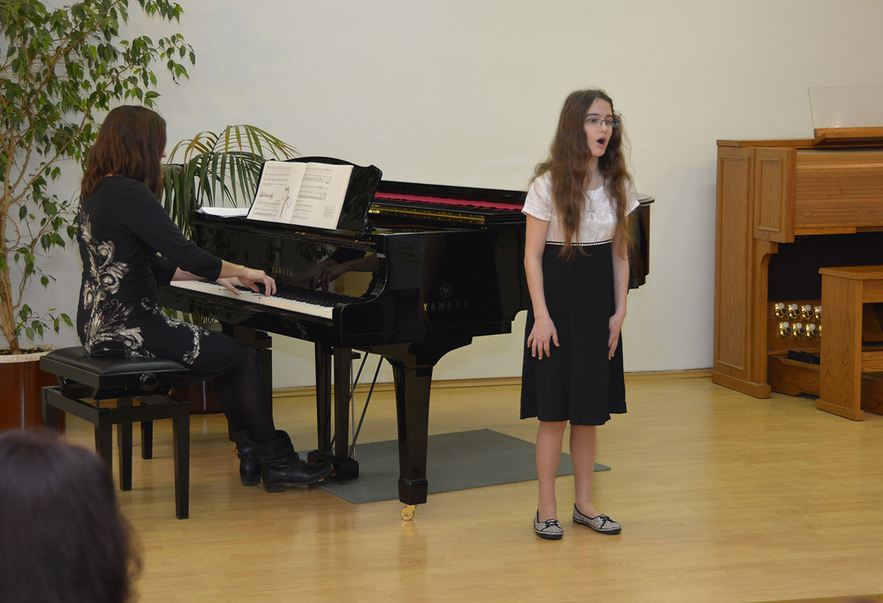 Barbora Brodníčková zpívá na podiu za doprovodu klavíru.